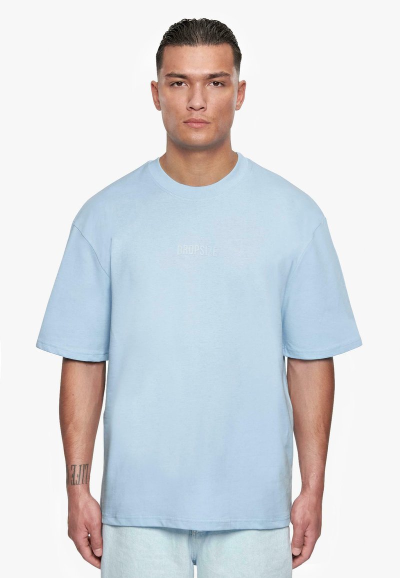 Lys blå oversized bomulls t-skjorte med rund hals og korte ermer, med "DROPSIZE" tekst i en kontrasterende font på brystet.