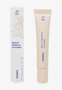 Correcteur Éclat Naturel dans un tube beige avec un capuchon strié, accompagné d'une boîte blanche arborant un motif abstrait clair et un texte bleu.