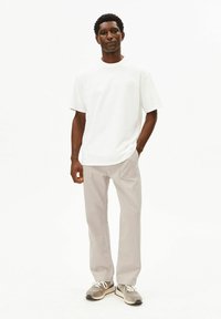 Wit T-shirt met korte mouwen, gecombineerd met lichtgrijze broek met rechte pijpen en grijze sneakers met crèmekleurige veters. Eenvoudig ontwerp en ontspannen pasvorm.