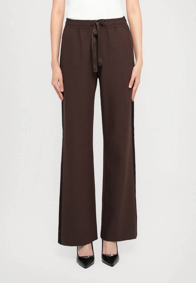 Pantalons larges marron avec une taille élastique et un lien de serrage, dotés de poches latérales et d'un tissu lisse et texturé.