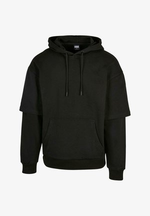 Melna kapuce ar kanguru kabatu, saistošā kapuce un īsām piedurknēm ar pagarinātiem dizaina elementiem. Izgatavota no mīksta, teksturēta auduma.