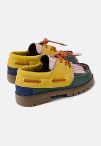 Multicolored shoes featuring yellow, green, navy, and pink leather. Rounded shape, rubber sole, with orange laces and stitching accents.