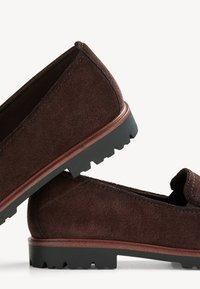 Mocasines de ante marrón con una superficie texturizada, suela de goma y un acento marrón contrastante alrededor del borde de la suela.