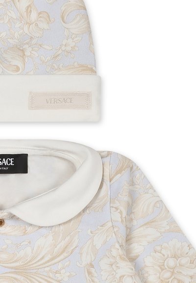 Beanie e top Versace in un tessuto blu chiaro con motivi floreali. Il beanie presenta un risvolto bianco e una patch con il logo; il top ha un collo bianco.