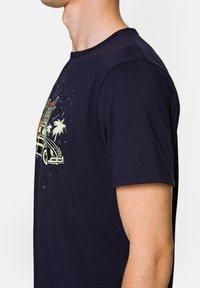 Granatowa bawełniana koszulka z krótkim rękawem, z klasycznym okrągłym dekoltem, z kolorowym nadrukiem przedstawiającym samochód w otoczeniu palm i ptaków.