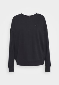 Sudadera negra de algodón suave con cuello redondo, puños acanalados y dobladillo. Presenta un pequeño logo bordado en rojo y blanco.