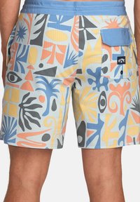 Shorts de bain en tissu bleu clair ornés de formes abstraites en orange, noir et jaune. Comprend une poche arrière et une taille contrastante.