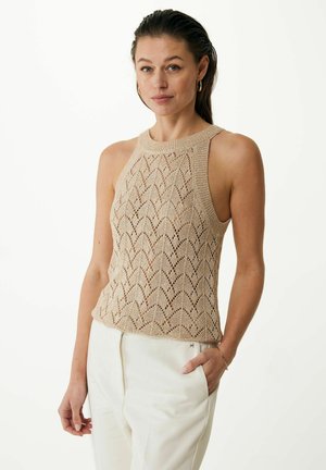 Knit sleeveless top in beige, featuring a textured zigzag pattern and a high neckline, paired with tailored white trousers.