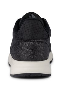Schwarzer Sportschuh mit strukturiertem Obermaterial, das ein reptilienartiges Muster aufweist, und einer kontrastierenden weißen Sohle. Flaches Design.