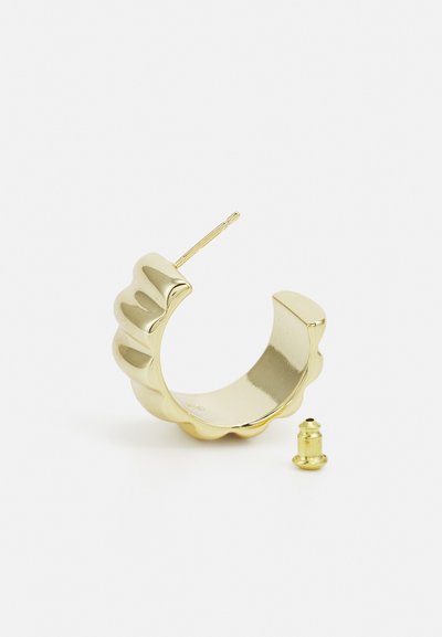 Gold hoop earring with a wavy edge design, featuring a narrow post and a small backing separate from the hoop. Smooth, shiny finish.