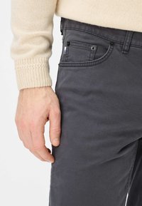 Graue Baumwollhose mit glatter Textur, ausgestattet mit Vorderseitenentaschen, verschlossen mit schwarzen Knöpfen und dezenten Nähdetails.