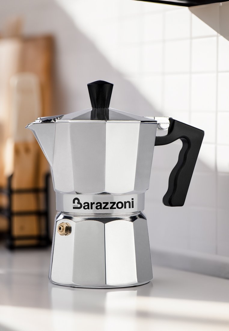 Edelstahlespressozubereiter mit sechseckiger Form, schwarzem Kunststoffgriff und einem auffälligen Logo. Verfügt über einen Ausguss und einen schwarzen Knopf.