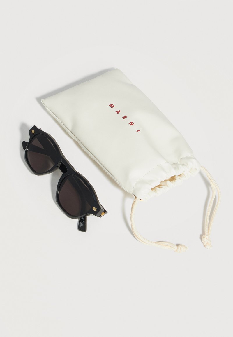 Occhiali da sole rettangolari neri con lenti scure accanto a una pochette bianca con coulisse, caratterizzata da testo rosso "MARNI" su uno sfondo chiaro.