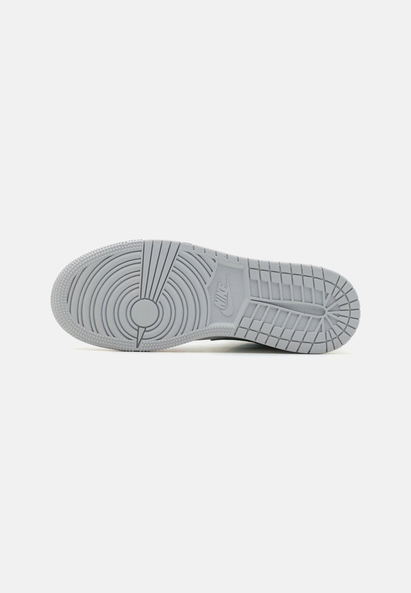 Suela de zapatilla Nike en gris claro, con patrones circulares y de banda, destacando el logo prominente de Nike y un acabado en goma texturizada.