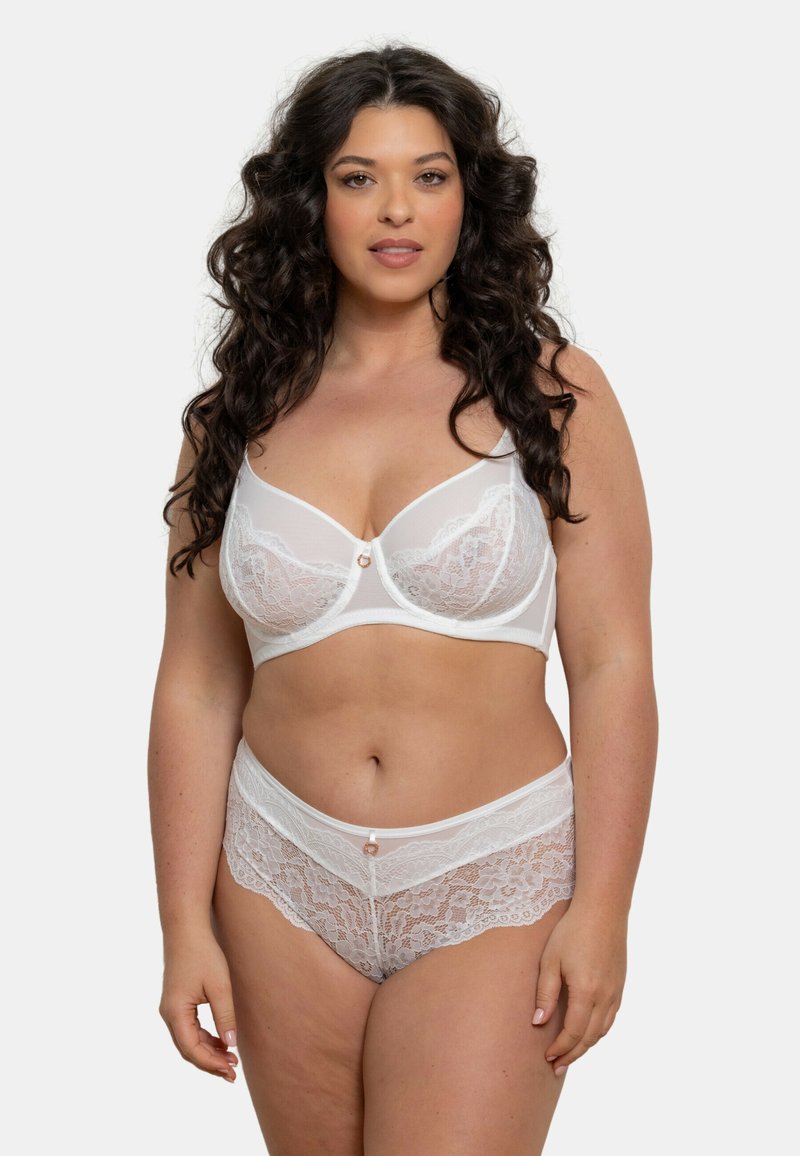 Ensemble soutiens-gorge en dentelle blanche et culottes taille haute en tissu semi-transparent, avec des bords festonnés et un petit bouton décoratif au centre.