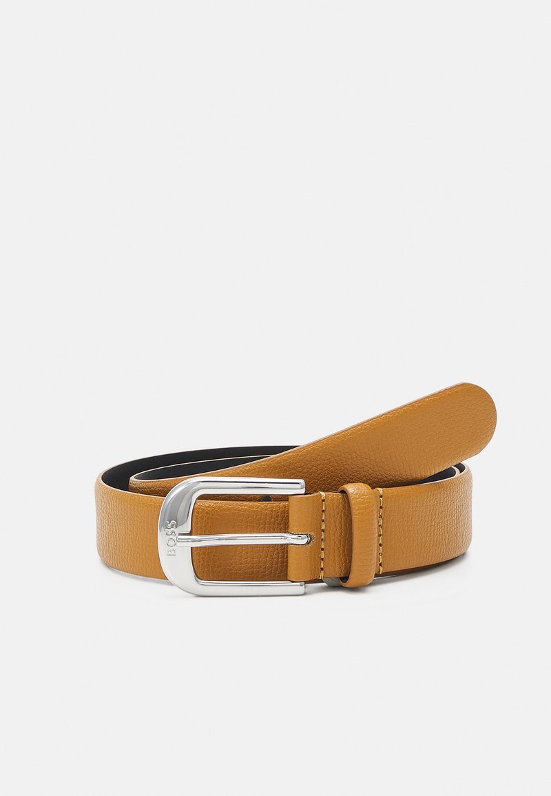 Cinto de couro castanho-claro com um acabamento texturizado, apresentando uma fivela prateada e detalhes de costura. A tira é afunilada, criando um design elegante.