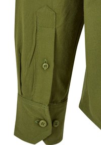 Manga de camisa verde oliva con cierre de botón, dos botones visibles y un corte angular reforzado en el puño. Tejido texturizado.