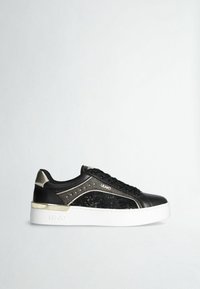 Baskets basses noires avec semelle plate-forme blanche, accents dorés, panneau de sequins sur le côté et lacets noirs sur un fond clair uni.