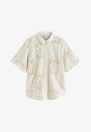 Blusa crema de manga corta con botones y un patrón patchwork de encaje floral y tela con ojales.