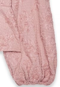 Tessuto rosa texturizzato con motivi floreali tridimensionali e un aspetto stropicciato, delicatamente arricciato all'orlo.