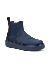 Botín de ante azul marino con paneles elásticos a los lados, una suela de plataforma gruesa y a juego, y una lengüeta para facilitar su uso. Textura suave en toda la superficie.