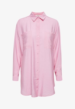 Világos rózsaszín, hosszú ujjú ing, amelynek galléros nyakkivágása van, két elülső zsebe és gombos záródása. Az anyag sima és enyhén fényes.