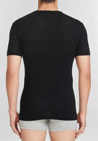 T-shirt nera a maniche corte realizzata in tessuto liscio. Forma aderente con collo a giro, cuciture visibili sulle spalle e sui bordi delle maniche.