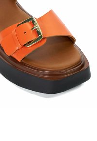 Brown platform sandal with thick black sole and wide orange leather strap featuring a gold buckle.