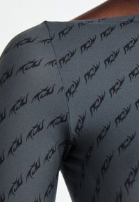Priljubljen top, ki se lepo prilega, v sivi tkanini z ponavljajočim se črnim vzorcem. Gladka tekstura z rahlim sijajem in širokim izrezom.