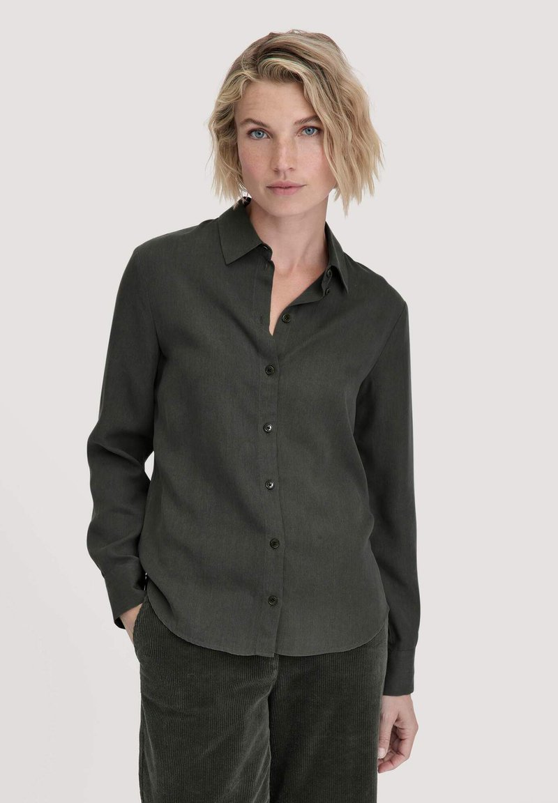 Camicia verde scuro con bottoni, realizzata in un tessuto liscio e testurizzato. Presenta un colletto classico e maniche lunghe, completata da bottoni neri.
