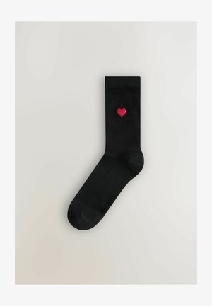 Čierne ponožky s hladkou textúrou, s malým vyšitým červeným srdiečkom na hornej strane. Klasický dizajn po členky.