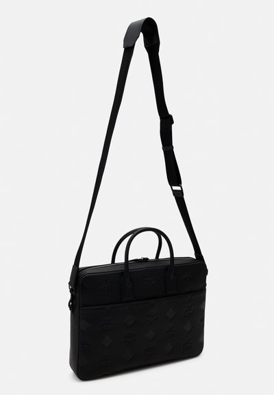 Malette noire en matériau texturé, dotée de deux poignées supérieures, d'une bandoulière réglable et d'une fermeture éclair noire. Détails de logo en motif sur toute la surface.