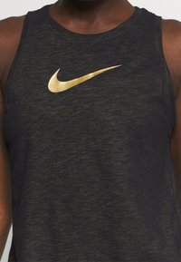 Černý bezrukávový sportovní top s zlatým logem Nike swoosh na hrudi, vyrobený z texturovaného, lehkého materiálu.