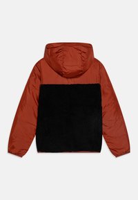 Hettejakke med en rødlig øvre del med blank finish og svart, strukturert fleece i bunnen. Elastiske mansjetter og hem.
