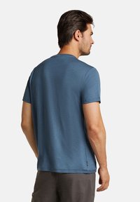 Klassinen crew-neck t-paita pehmeästä, tekstuurista, savitummaisen sinisestä kankaasta. Lyhyet hihat, rento leikkaus, pienen etiketti tarran kanssa helman lähellä.