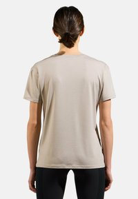 Beige cotton t-shirt with short sleeves and a round neckline, featuring a smooth texture and a relaxed fit, viewed from the back.