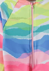 Maillot de bain une pièce coloré avec fermeture éclair à l'avant, présentant des motifs ondulés en vert, bleu, rose et blanc ; fabriqué en matériau lisse et extensible.