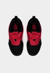 Baskets avec une base noire, des lacets rouges froncés et une semelle en caoutchouc texturée. Comprend un logo sur la semelle intérieure et une languette à l'arrière du talon.