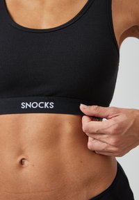 Schwarzer Sport-BH aus glattem Stoff, mit passgenauer Passform und einem elastischen Band mit dem Aufdruck "SNOCKS" in weiß.