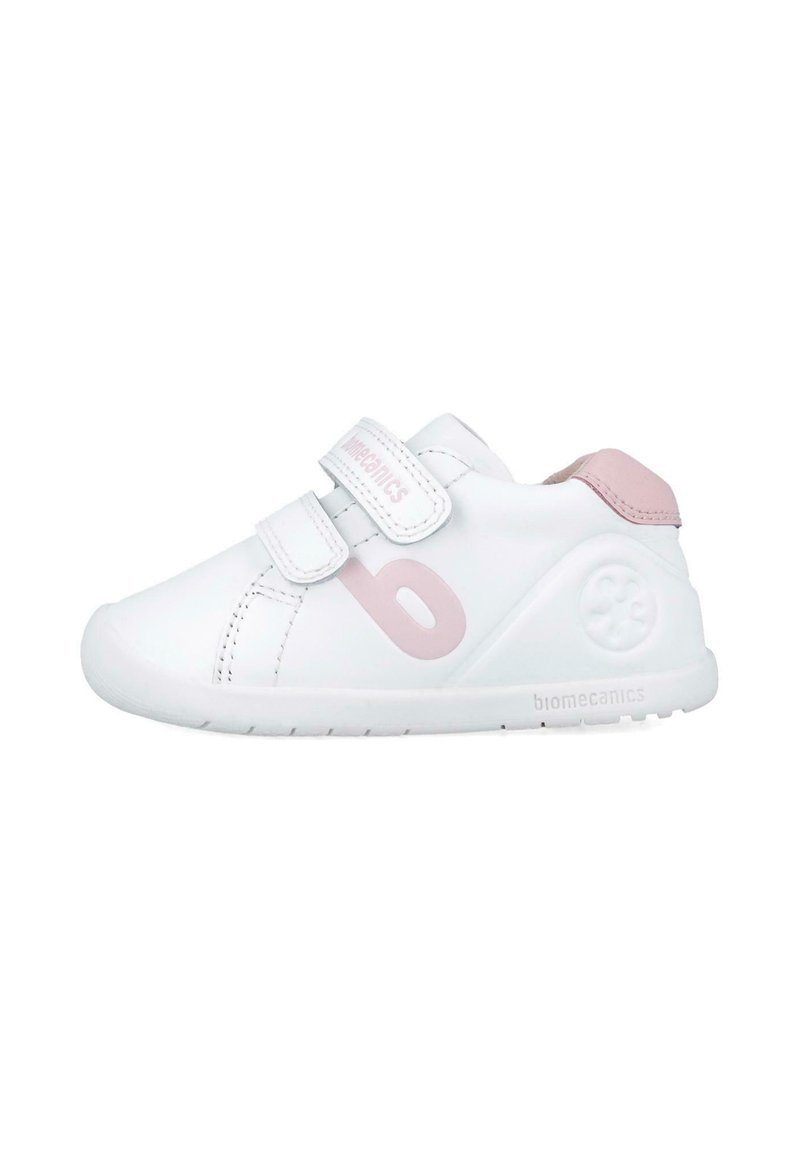 Zapatilla blanca con acentos en rosa, que cuenta con dos correas de Velcro, una puntera redondeada y un logo en el lateral. Fabricada con material sintético suave.
