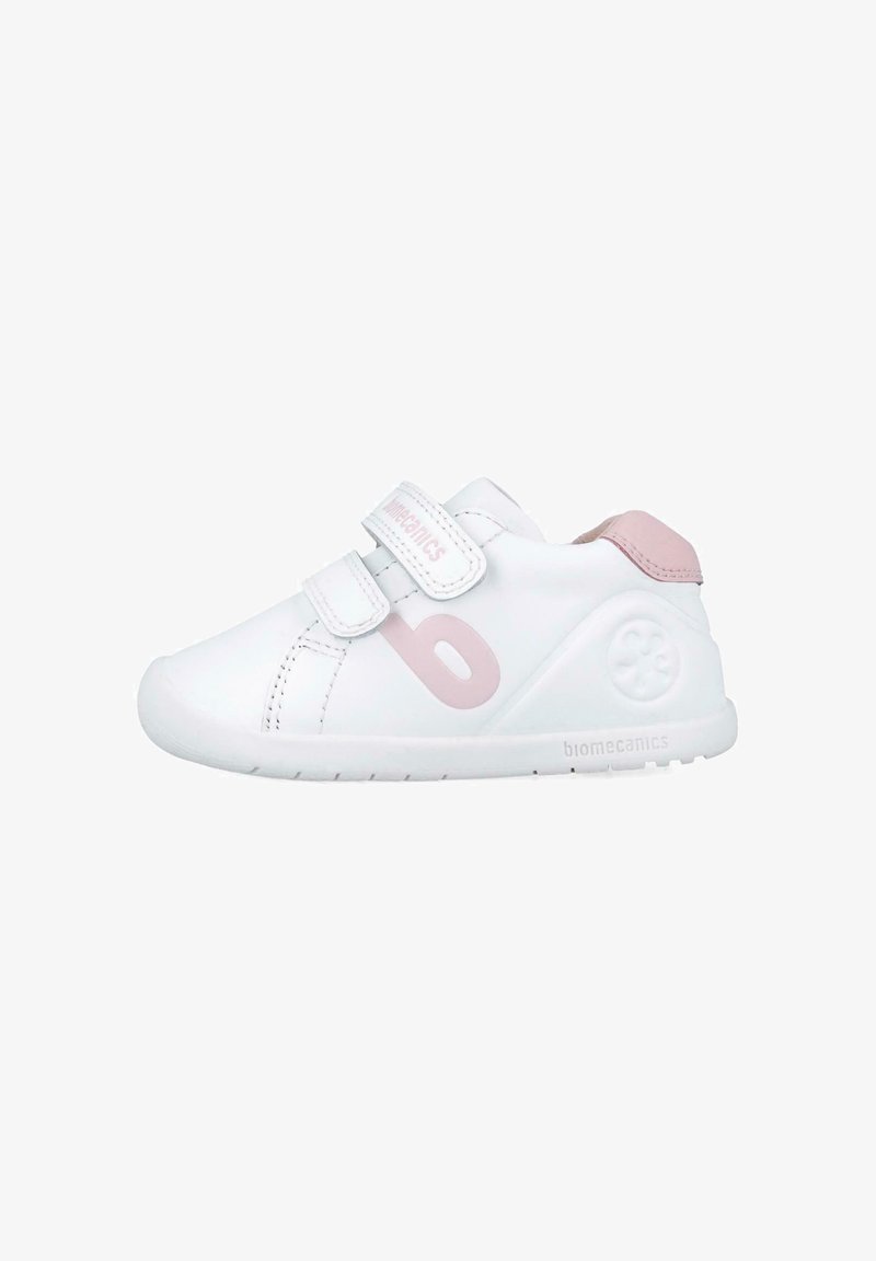 Zapatilla blanca con acentos en rosa, que cuenta con dos correas de Velcro, una puntera redondeada y un logo en el lateral. Fabricada con material sintético suave.