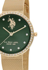 Orologio con cinturino in mesh dorato e quadrante verde a raggi di sole. Presenta accenti dorati, un logo, testi stampati e una lunetta tempestata di cristalli.