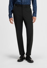 Black dress trousers with a tailored fit, featuring belt loops and a smooth texture. Paired with a patterned blue button-up shirt and black shoes.