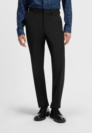 Black dress trousers with a tailored fit, featuring belt loops and a smooth texture. Paired with a patterned blue button-up shirt and black shoes.