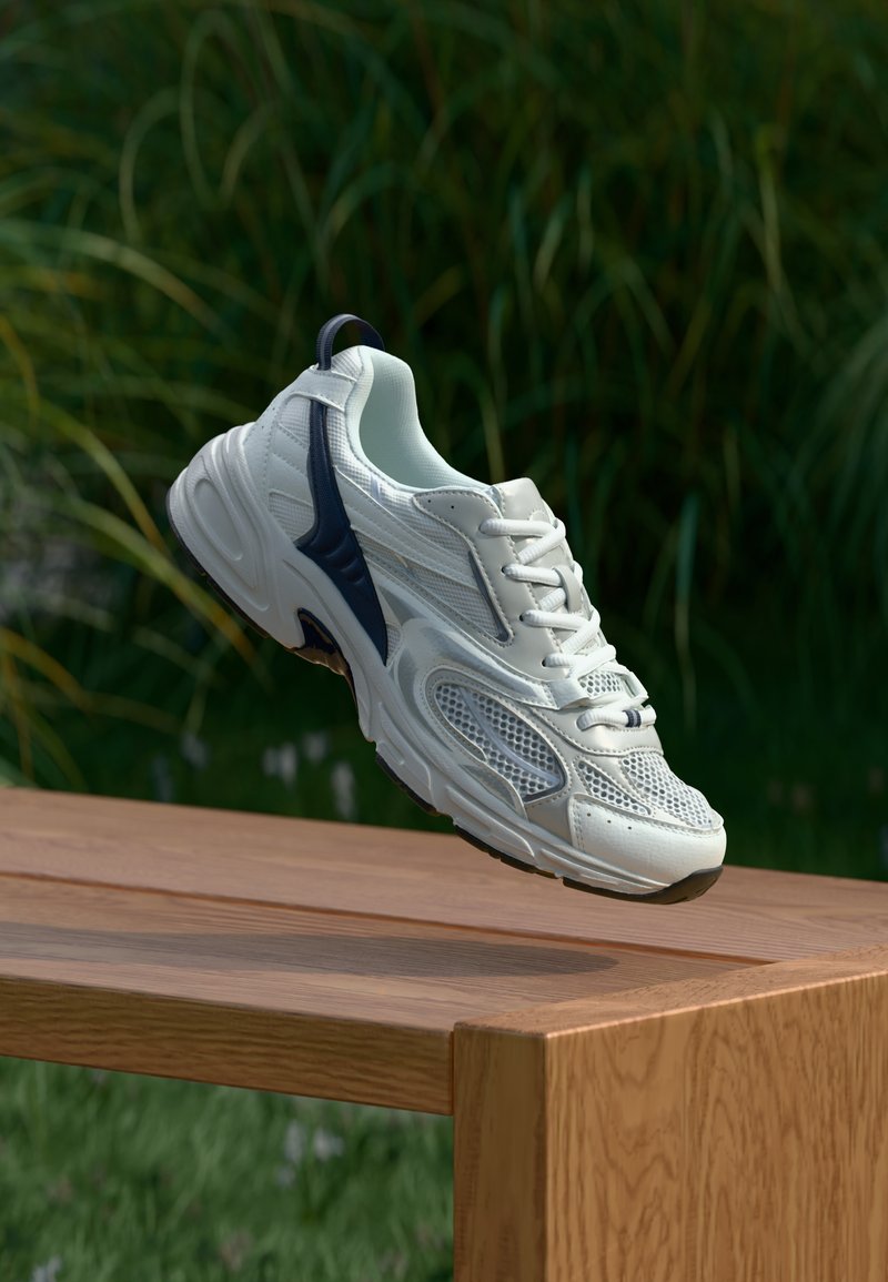 Λευκό αθλητικό παπο ύτσι με πάνελ από δίχτυ, ναυτικά στοιχεία, στρογγυλή μύτη και σχέδιο με κορδόνια, τοποθετημένο σε ξύλινη επιφάνεια με πράσινο φόντο.