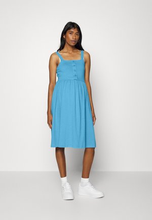 Um vestido sem mangas de um tom azul claro, com um corpete justo, detalhe de botões na parte da frente e uma saia rodada. Feito de um tecido suave.
