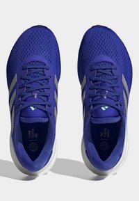 Blue athletic shoes with a breathable mesh upper, three silver stripes, and a white outsole. Includes "END PLASTIC WASTE" text on the insole.