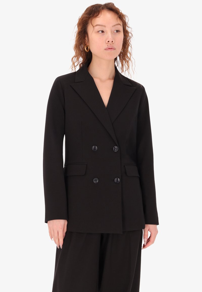 Blazer doppiopetto nero con rever a sodini, caratterizzato da due tasche frontali e dettagli in bottone. Tessuto liscio e strutturato, vestibilità sartoriale.