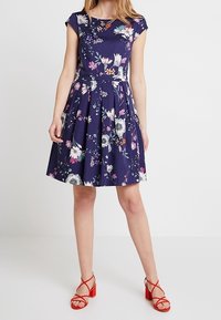 Knee-langes Kleid mit Blumenmuster aus dunkelblauem Stoff, mit kurzen Ärmeln und tailliertem Oberteil, das einen geplusterten Rock und florale Akzente aufweist.
