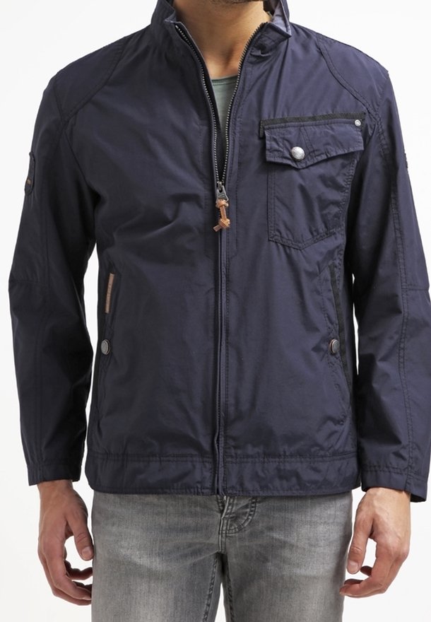 Navyblauw lichtgewicht jack met een staande kraag, ritssluiting aan de voorkant en borstzak met drukknoop. Gladde textuur, casual ontwerp.